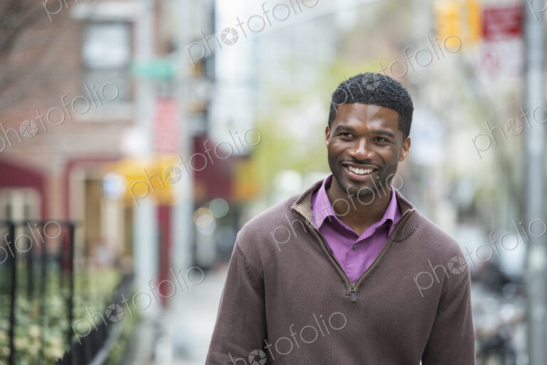 Outdoors in the city in spring. An urban lifestyle. A young man wearing a purple shirt…