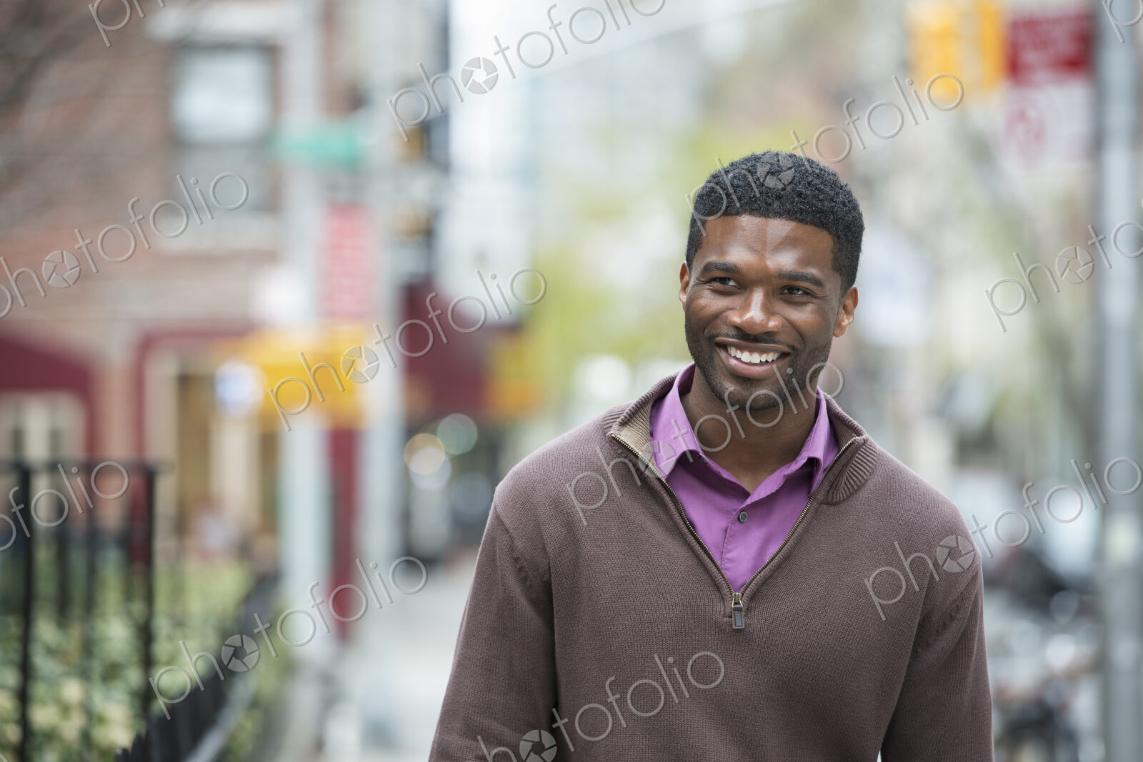Outdoors in the city in spring. An urban lifestyle. A young man wearing a purple shirt…