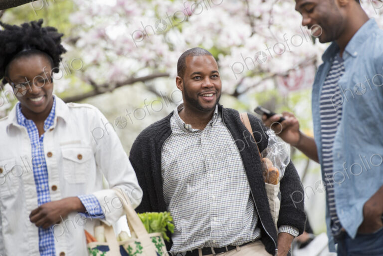 Outdoors in the city in spring. An urban lifestyle. Three people in the park. One man…