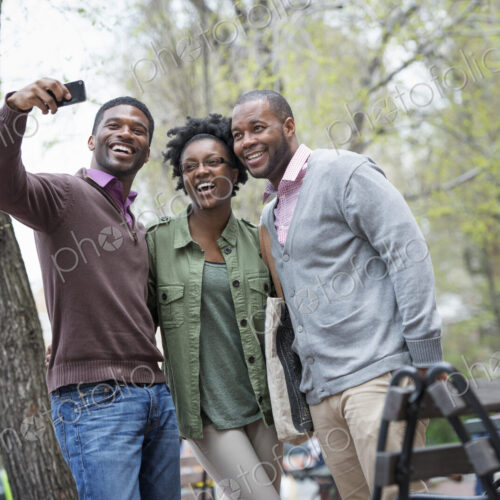 Outdoors in the city in spring. An urban lifestyle. Three people posing together and… Outdoors in the city in spring. An urban lifestyle. Three people posing together and…