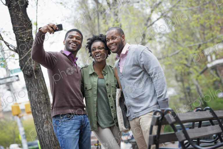 Outdoors in the city in spring. An urban lifestyle. Three people posing together and…