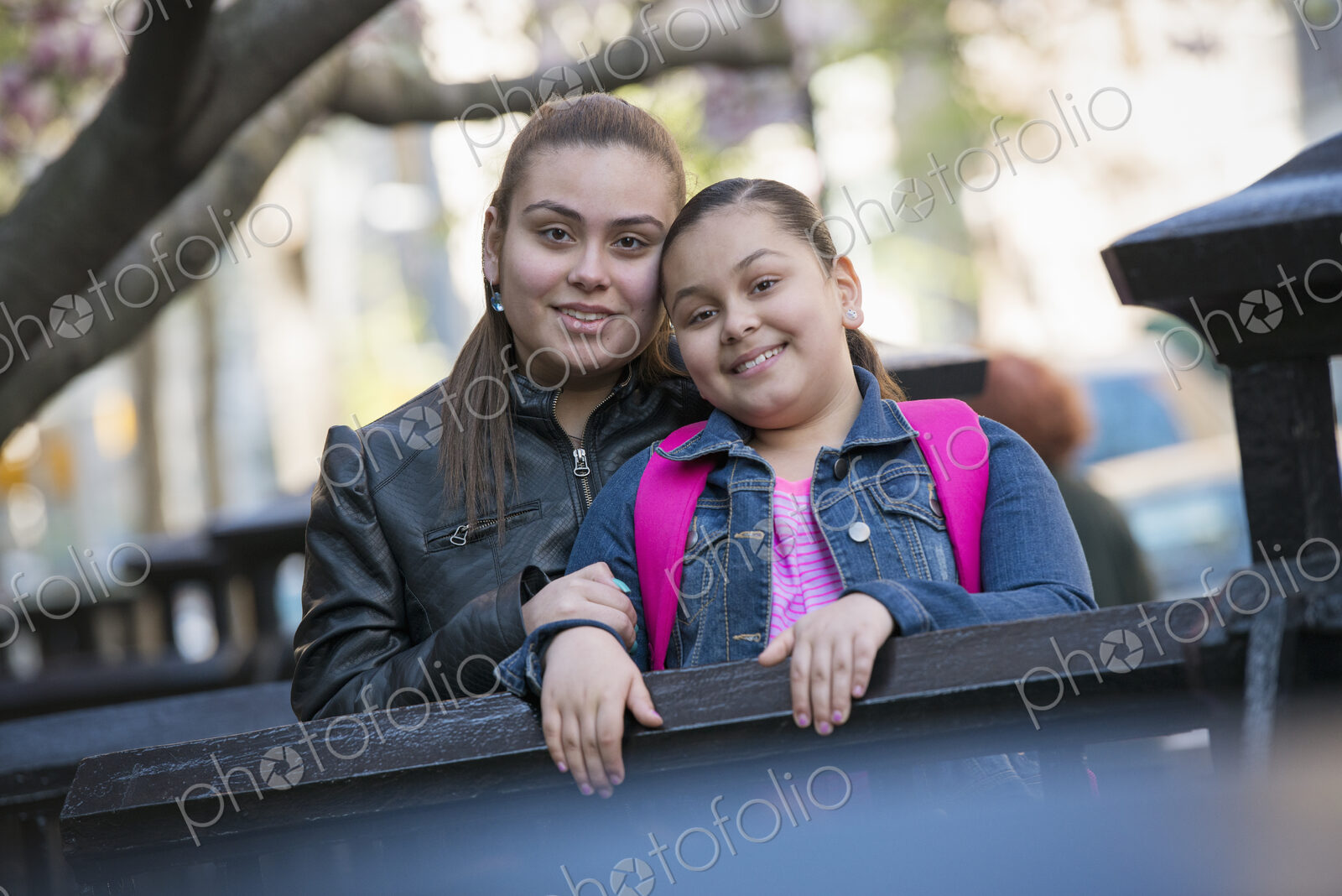 Outdoors in the city in spring. An urban lifestyle. Two children side by side, with…