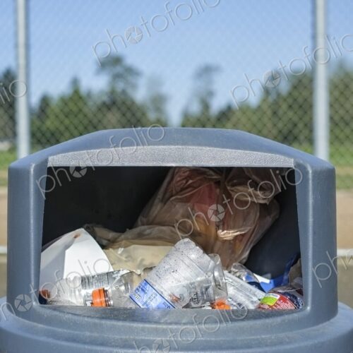 Overflowing trash in trashcan at sports field