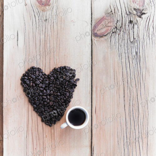 Overhead view of a heap of roasted organic coffee beans in a heart shape, arranged on… Overhead view of a heap of roasted organic coffee beans in a heart shape, arranged on…