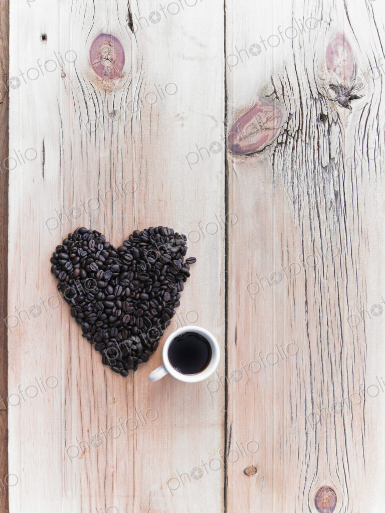 Overhead view of a heap of roasted organic coffee beans in a heart shape, arranged on…