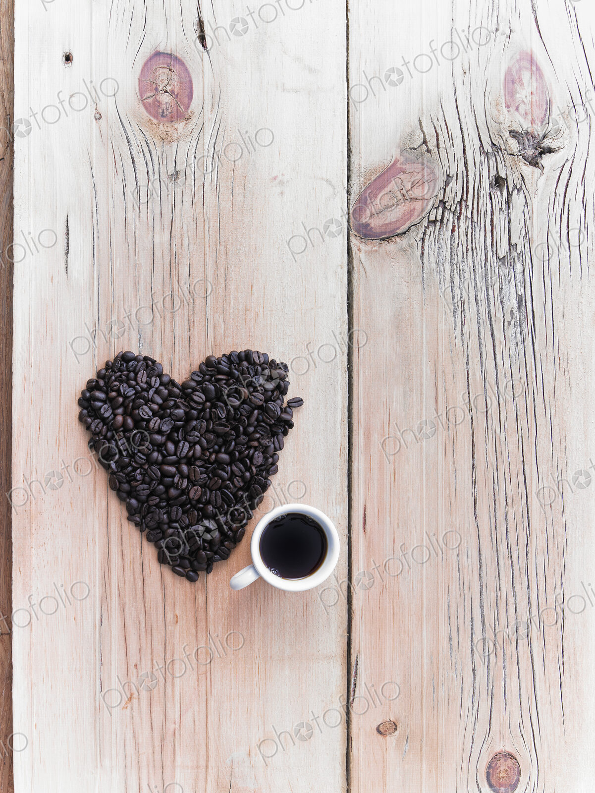 Overhead view of a heap of roasted organic coffee beans in a heart shape, arranged on…