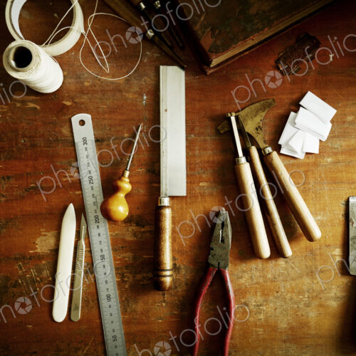 Overhead view of a workbench with hand tools for bookbinding.