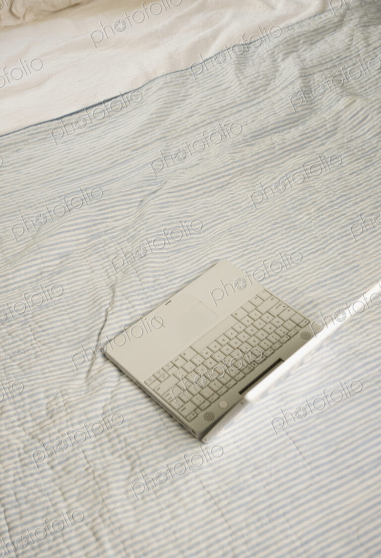 Overhead view of open laptop on bed.