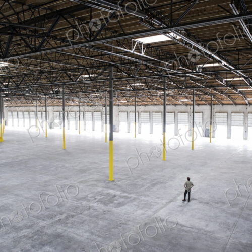 Owner checking out the new interior of a large empty warehouse space. Owner checking out the new interior of a large empty warehouse space.