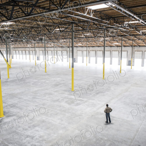 Owner checking out the new interior of a large empty warehouse space. Owner checking out the new interior of a large empty warehouse space.