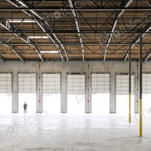 Owner silhouetted and standing in a loading dock door for a new empty warehouse. Owner silhouetted and standing in a loading dock door for a new empty warehouse.