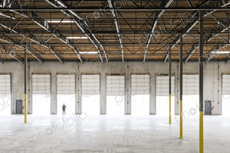 Owner silhouetted and standing in a loading dock door for a new empty warehouse.