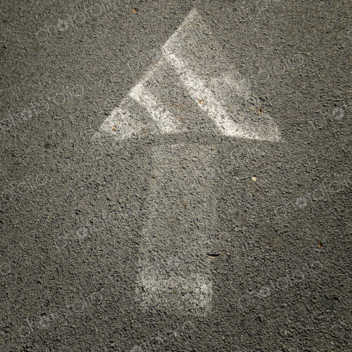 Painted arrow symbol on a pavement, faded paintwork.