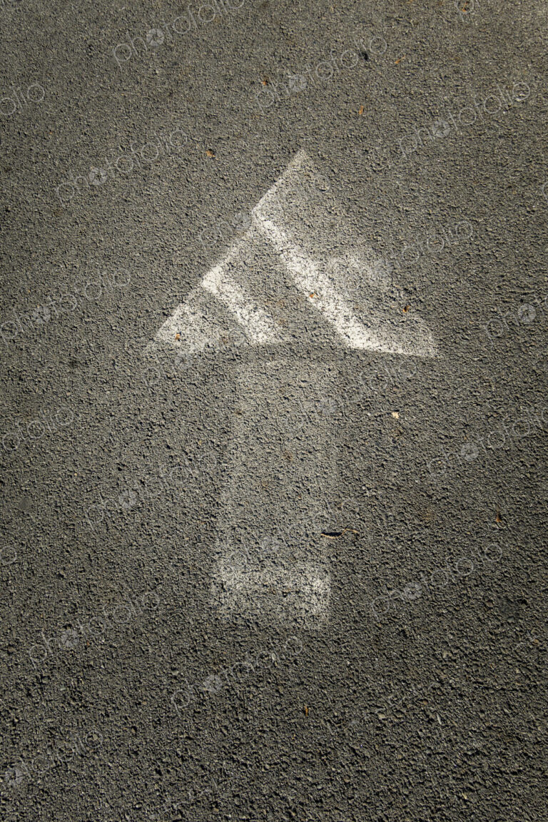 Painted arrow symbol on a pavement, faded paintwork.