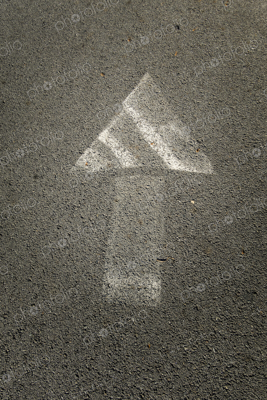 Painted arrow symbol on a pavement, faded paintwork.