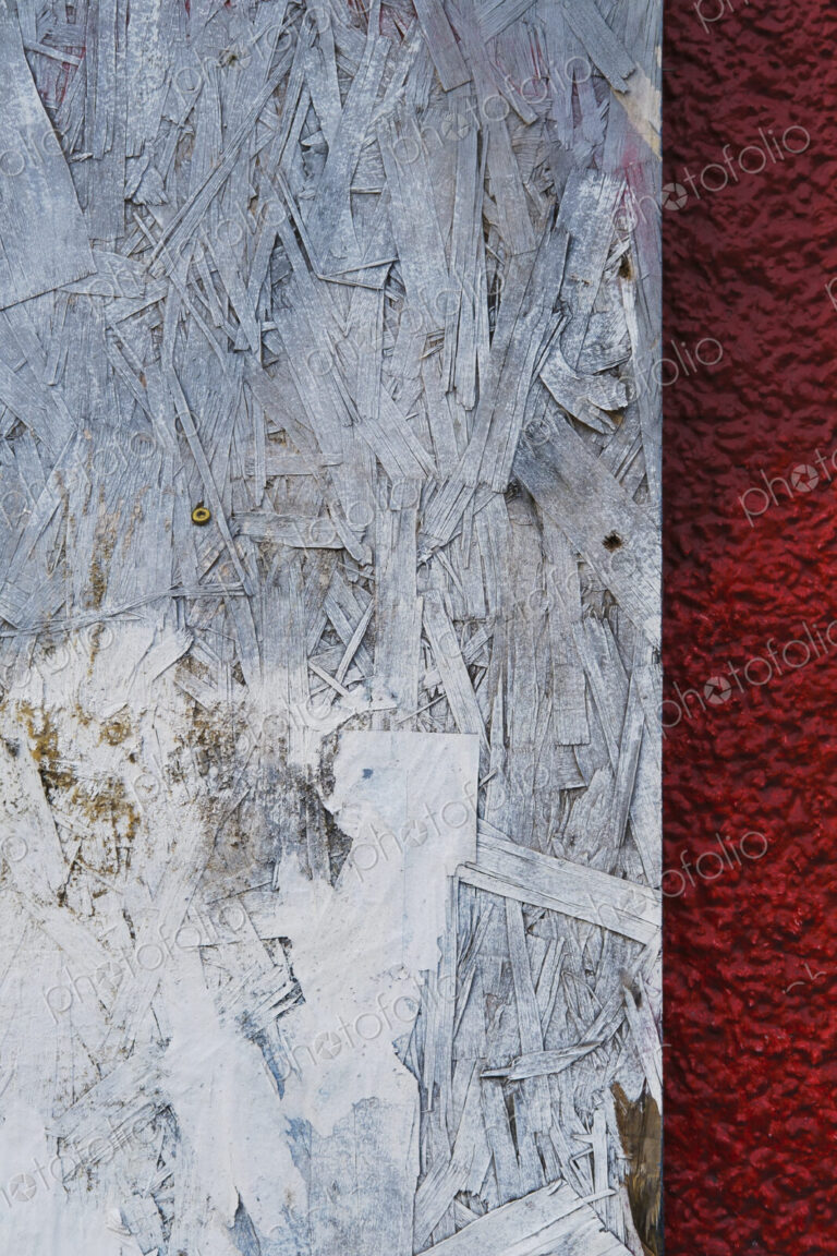Painted white particle board against red stucco