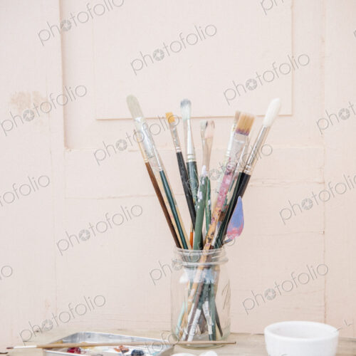 Painting materials, glass jar with paint brushes, paint tubes and a bowl. Painting materials, glass jar with paint brushes, paint tubes and a bowl.