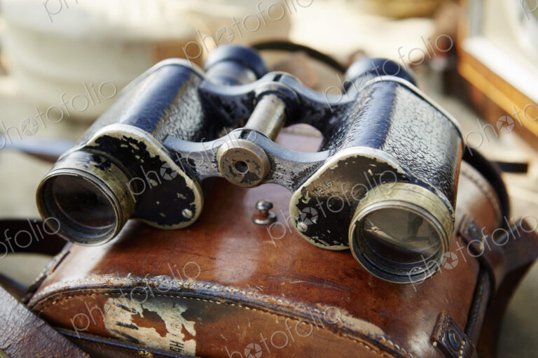 Pair of vintage binoculars with a worn leather case at a flea market.