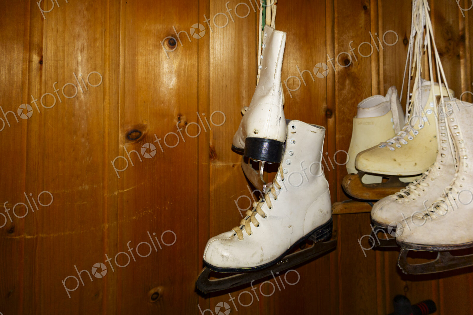 Pairs of ice skates hanging up in a room.