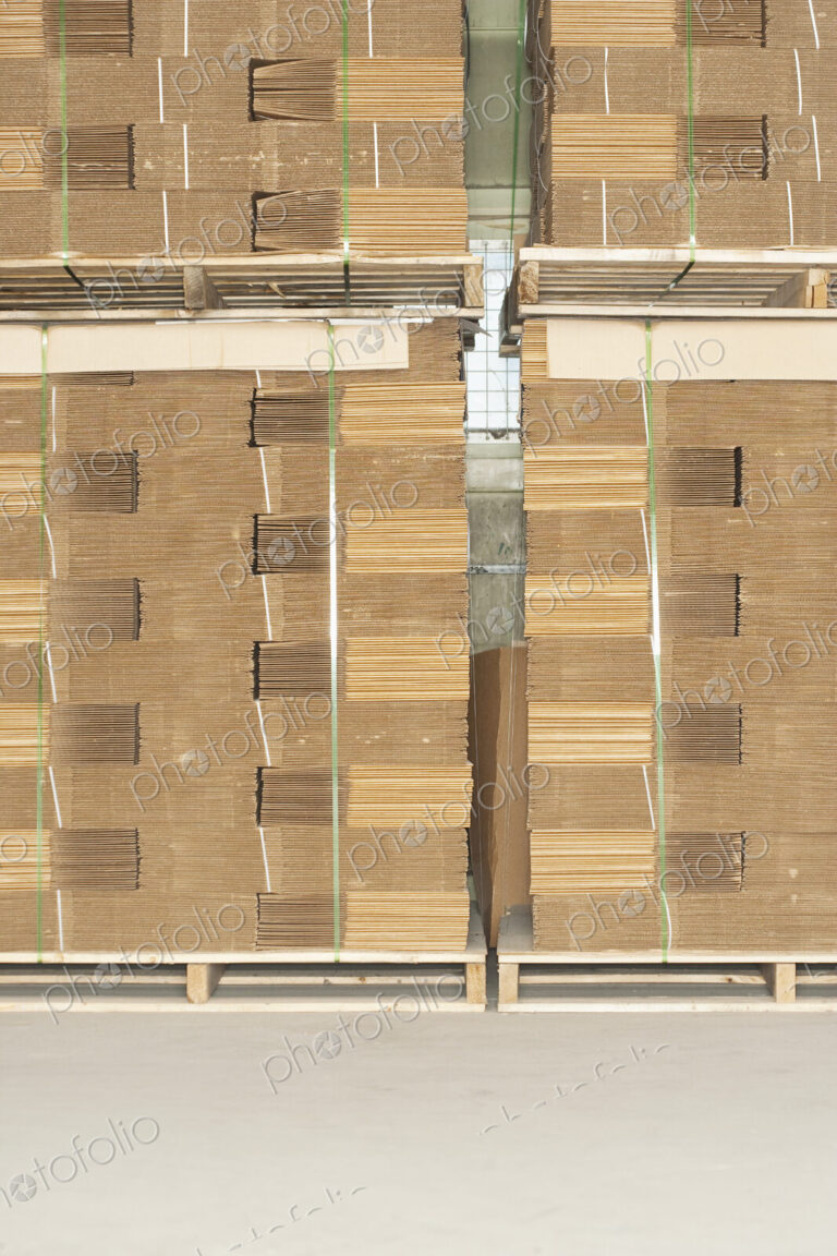 Pallets of flat folded cardboard boxes.
