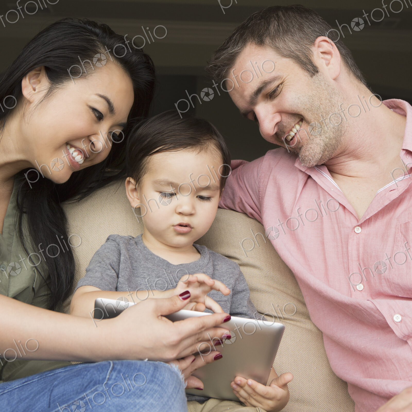 Parents with their young son, looking at a digital tablet.