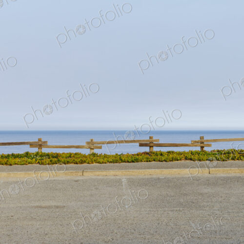 Parking lot with fencing and ice plant invasive ground cover, by the ocean