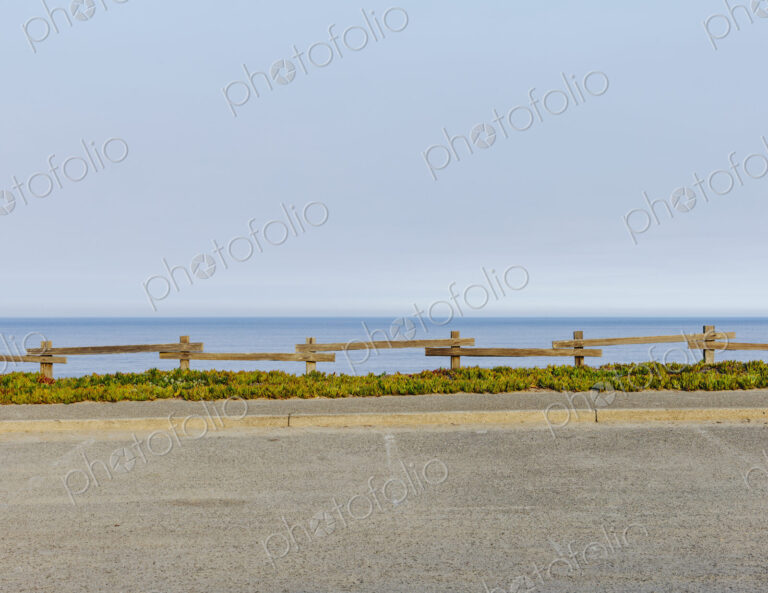 Parking lot with fencing and ice plant invasive ground cover, by the ocean
