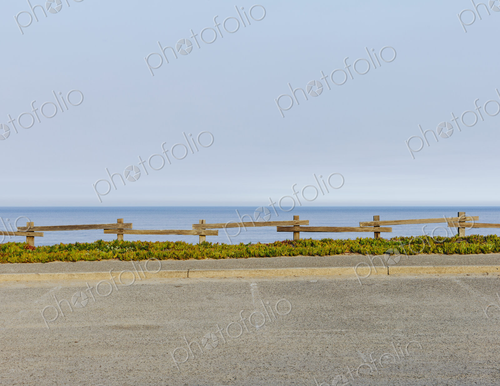 Parking lot with fencing and ice plant invasive ground cover, by the ocean