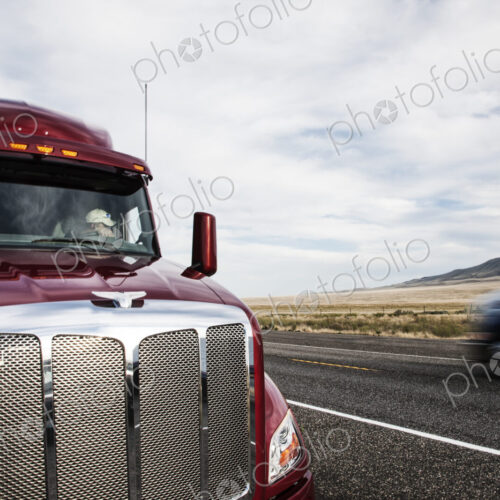 Partial view of the cab on a commercial truck and the highway.