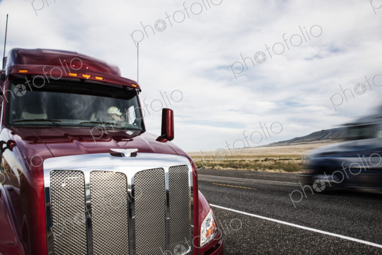 Partial view of the cab on a commercial truck and the highway.