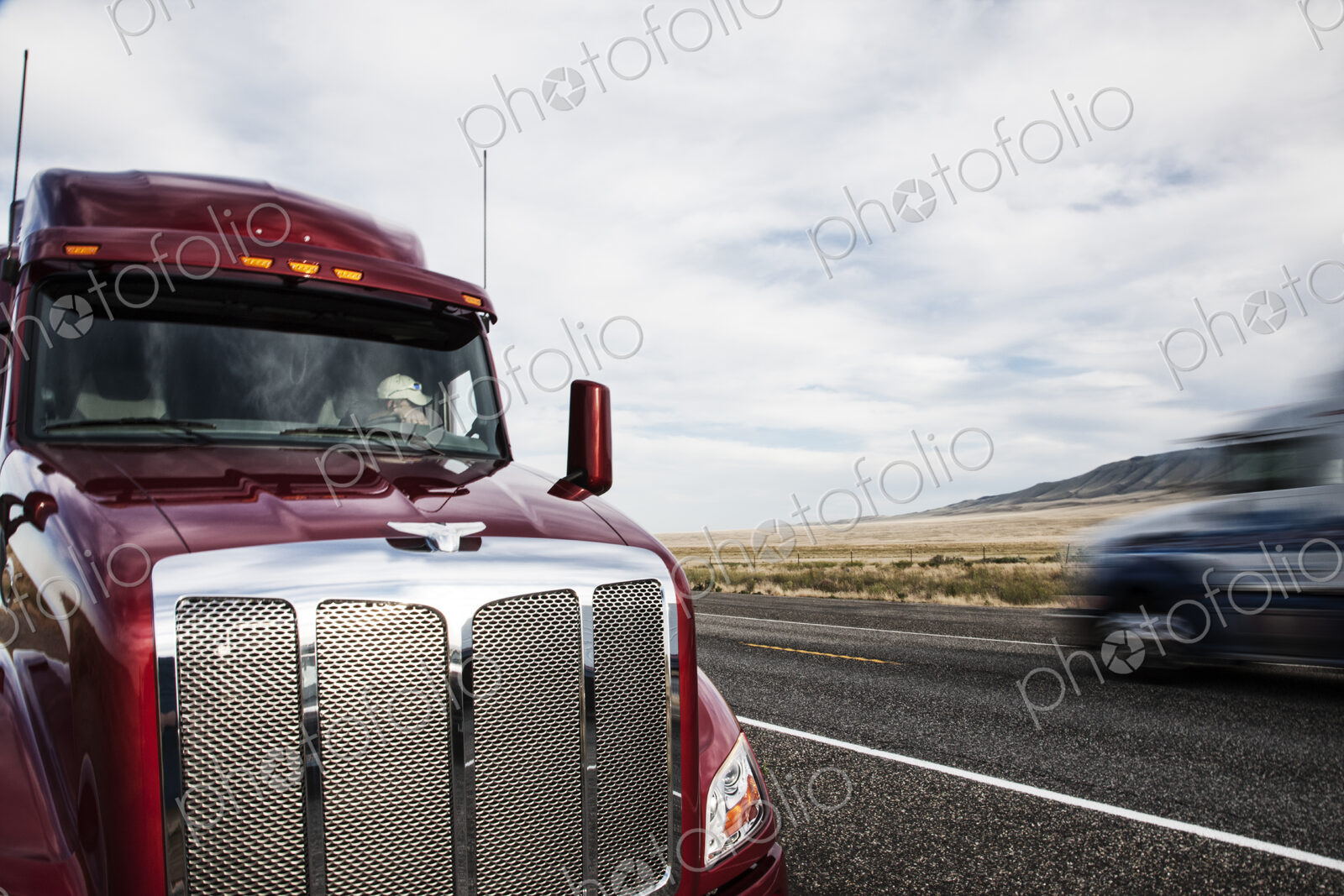 Partial view of the cab on a commercial truck and the highway.