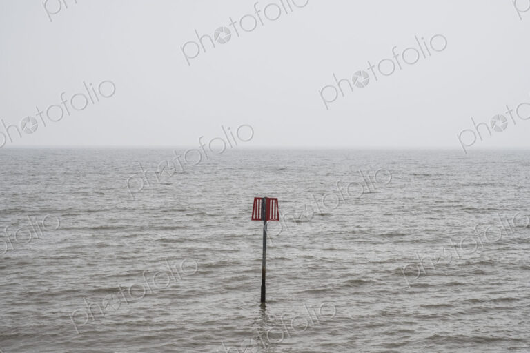 Partially submerged metal marker pole in the ocean.