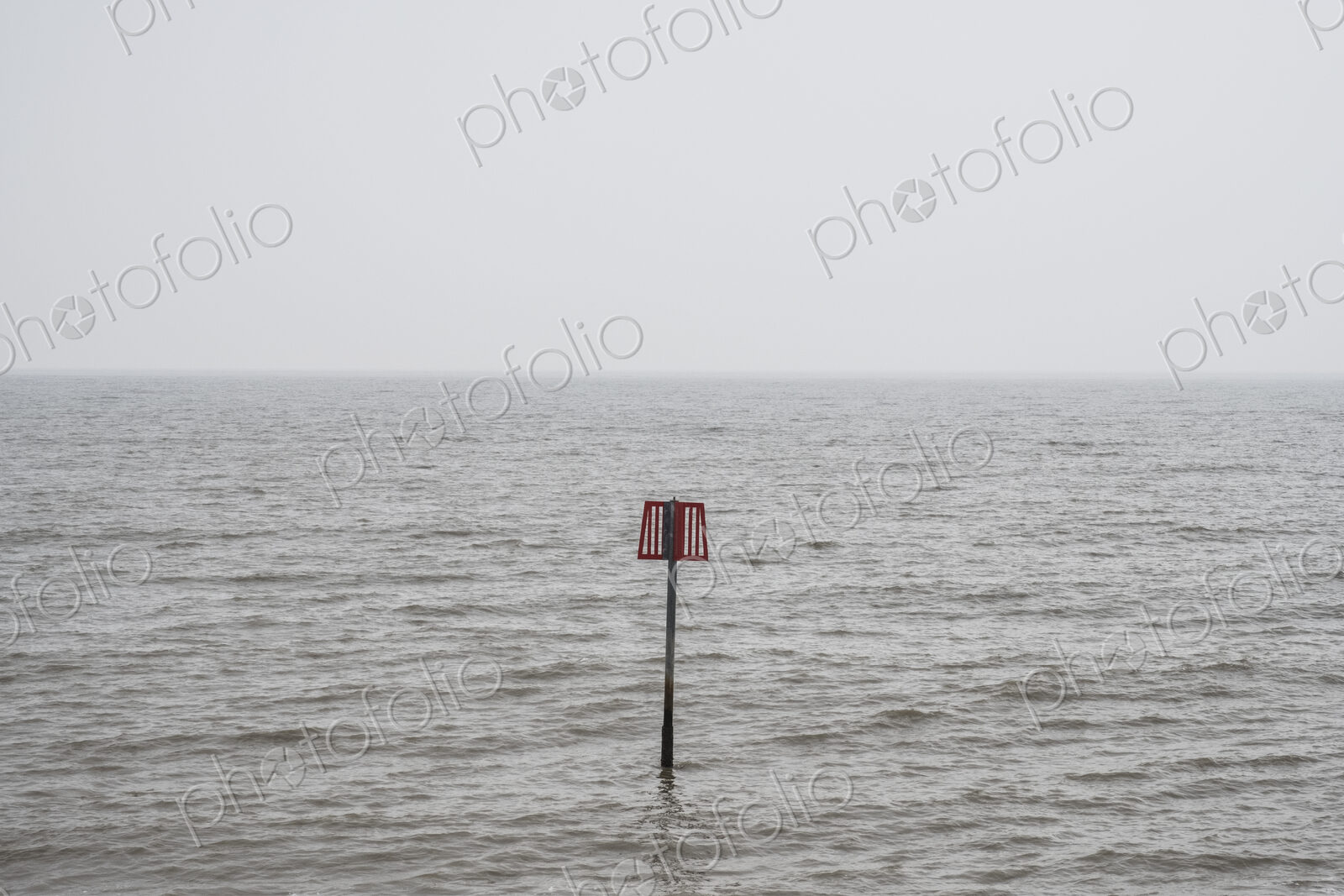 Partially submerged metal marker pole in the ocean.