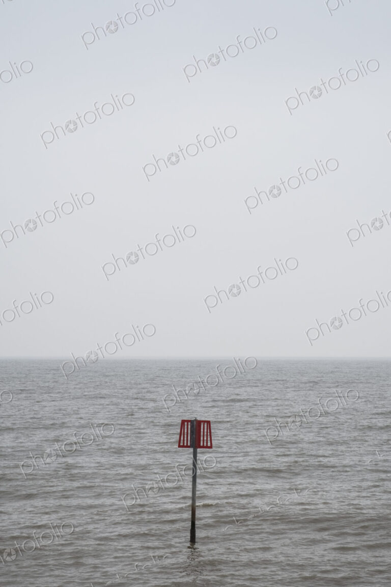 Partially submerged metal marker pole in the ocean.