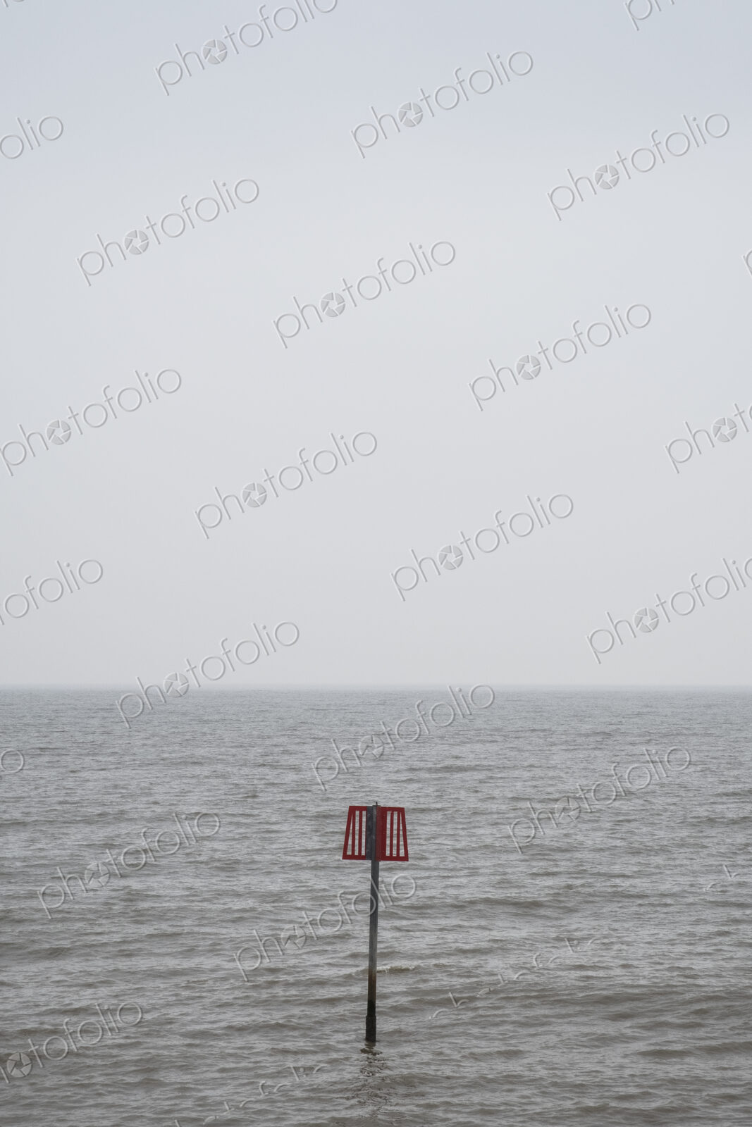 Partially submerged metal marker pole in the ocean.