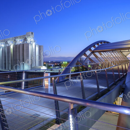 Pedestrian bridge and factory lit up at night Pedestrian bridge and factory lit up at night