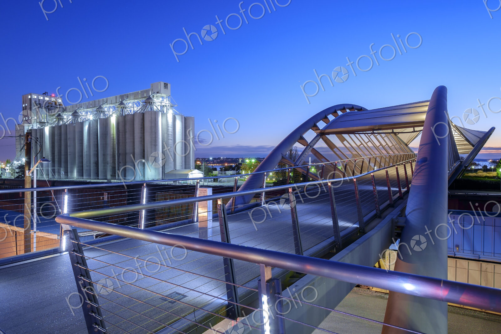 Pedestrian bridge and factory lit up at night