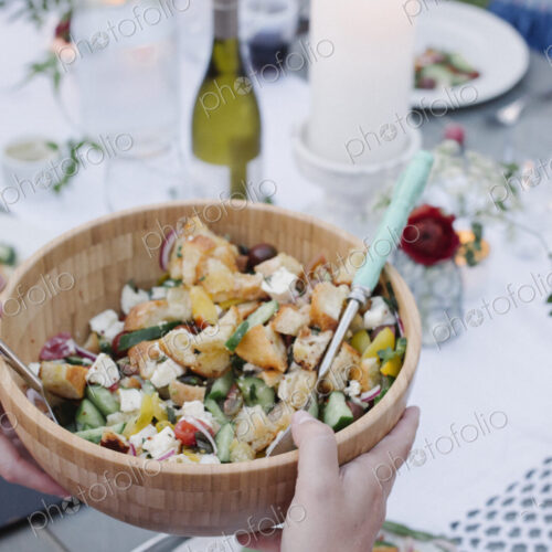 People around a table at a garden party, a bowl of salad.