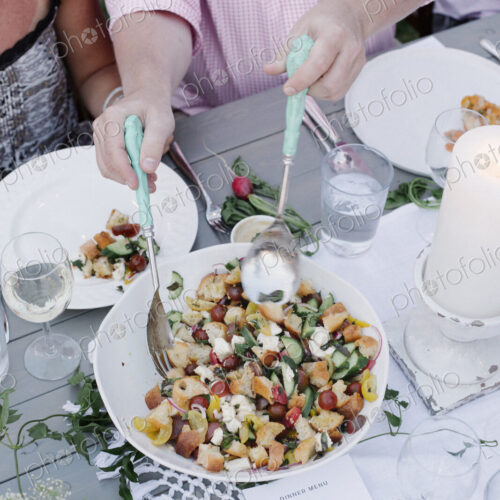People around a table at a garden party, a bowl of salad.