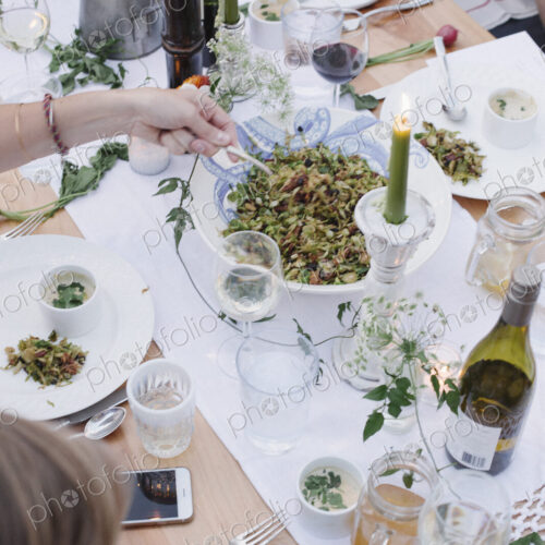 People around a table at a garden party, a bowl of salad.