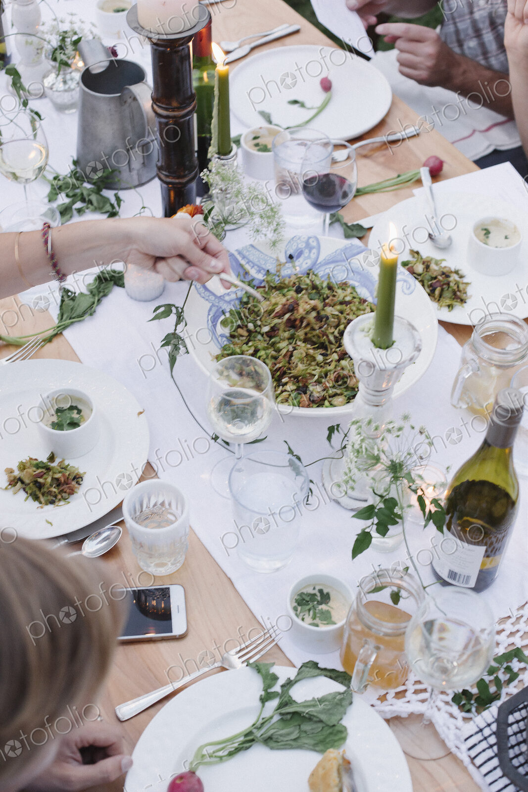 People around a table at a garden party, a bowl of salad.