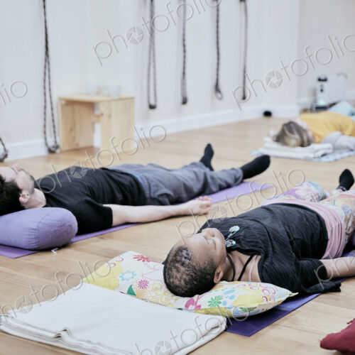 People lying down on an exercise studio floor relaxing after a sound therapy session