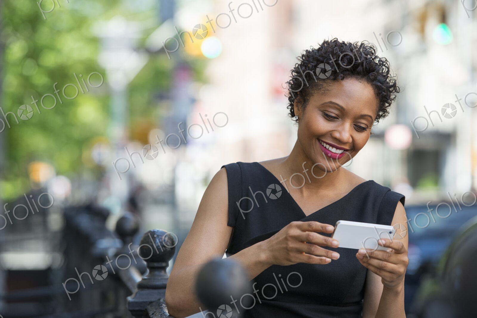 People on the move. A woman in a black dress on a city street, checking her phone.