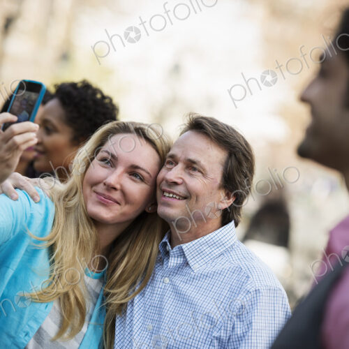 People outdoors in the city in spring time. A woman using her cell phone to take a… People outdoors in the city in spring time. A woman using her cell phone to take a…