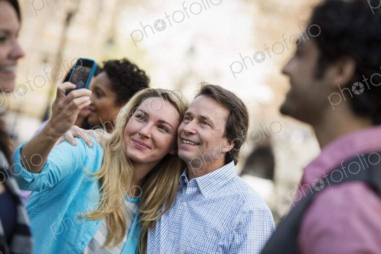 People outdoors in the city in spring time. A woman using her cell phone to take a…