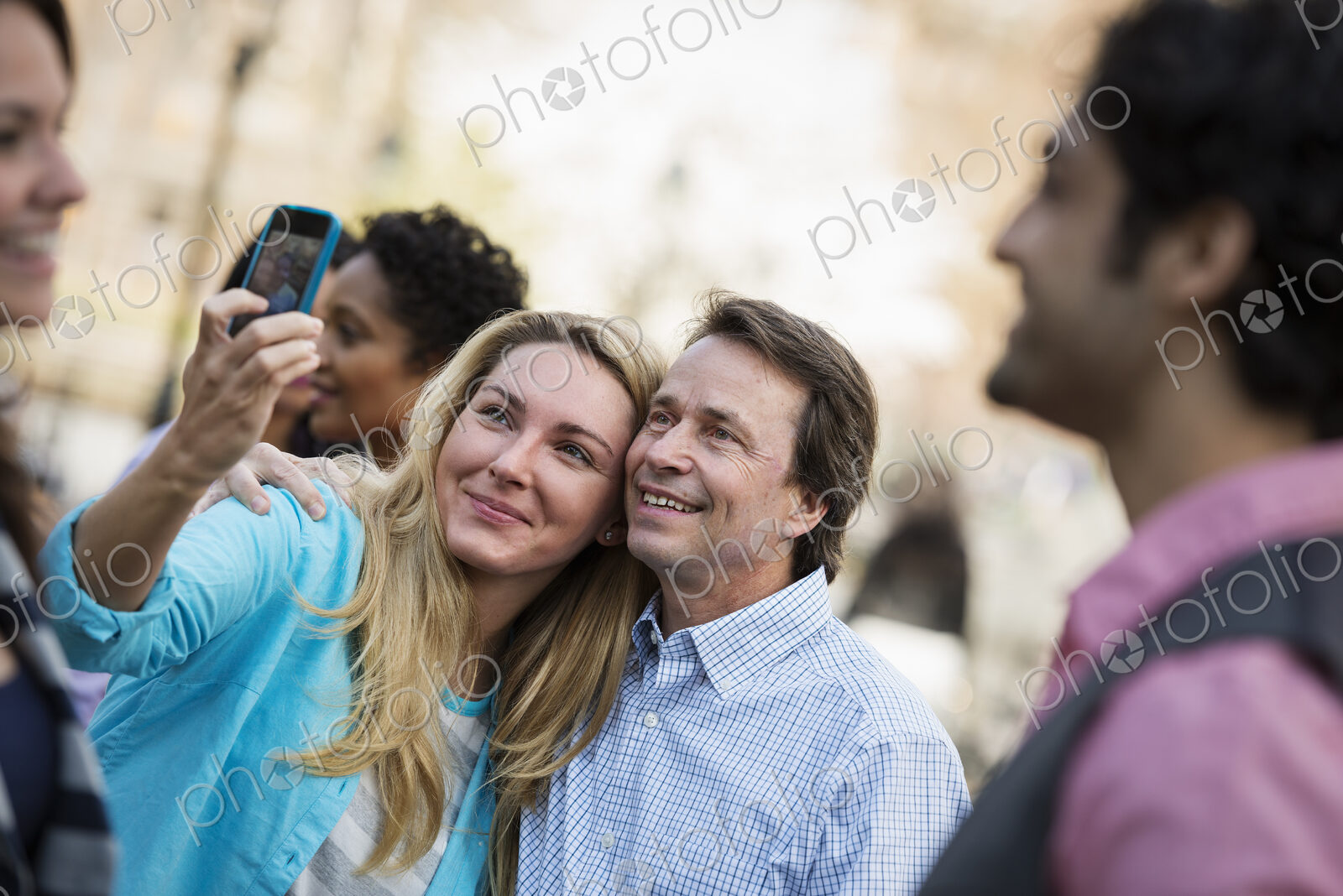 People outdoors in the city in spring time. A woman using her cell phone to take a…