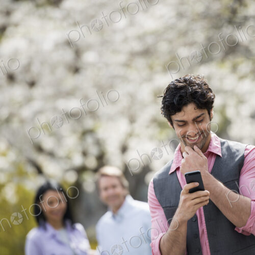 People outdoors in the city in spring time. Cherry blossom on the trees. A man…