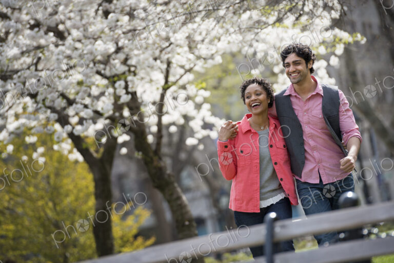 People outdoors in the city in spring time. New York City park. A man and woman side…