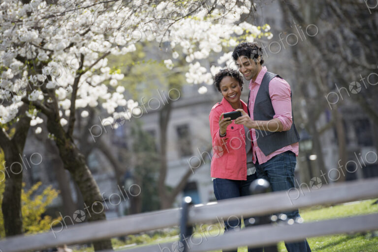 People outdoors in the city in spring time. New York City park. A man and woman side…