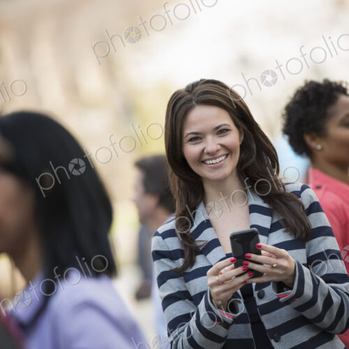 People outdoors in the city in spring time. New York City park. A young woman holding… People outdoors in the city in spring time. New York City park. A young woman holding…